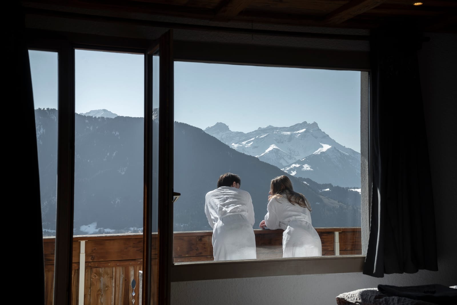 Couple en peignoirs admirant les Alpes depuis la chambre