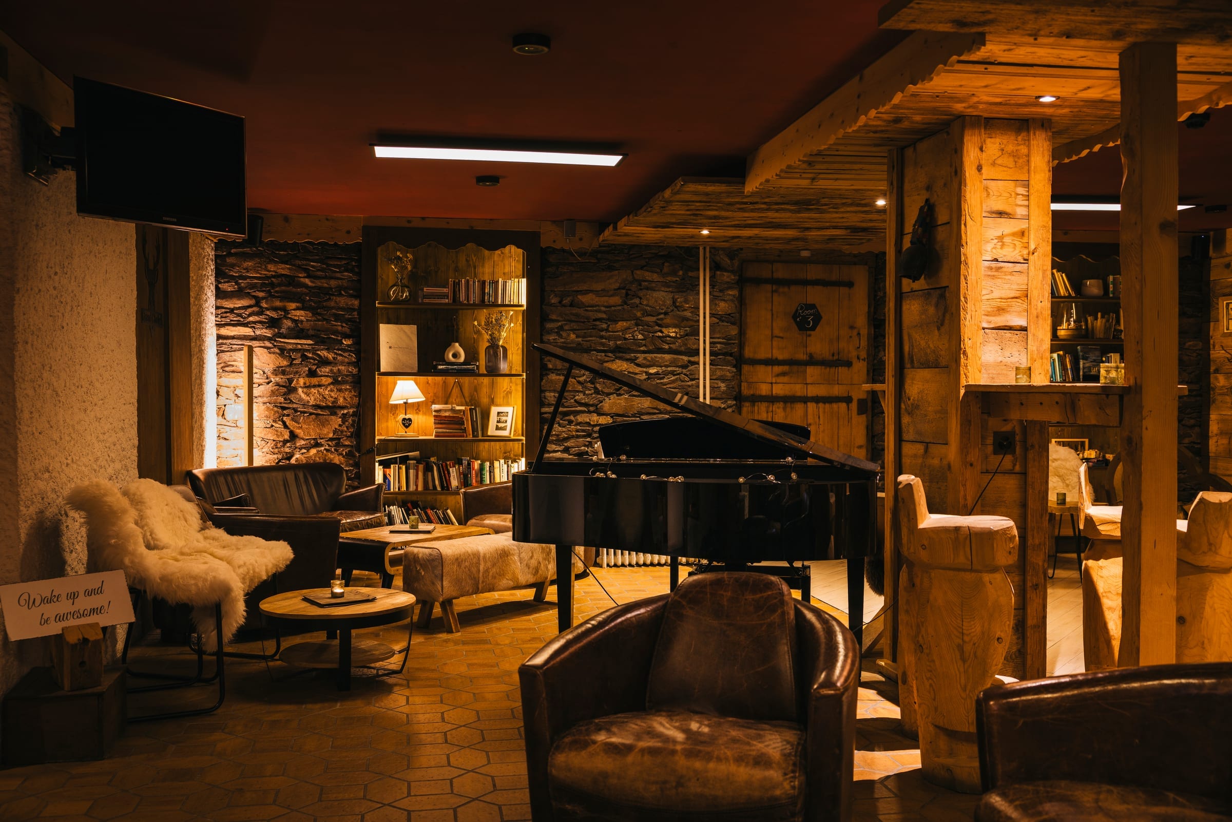 Salon lounge avec piano et mur en pierre, ambiance feutrée