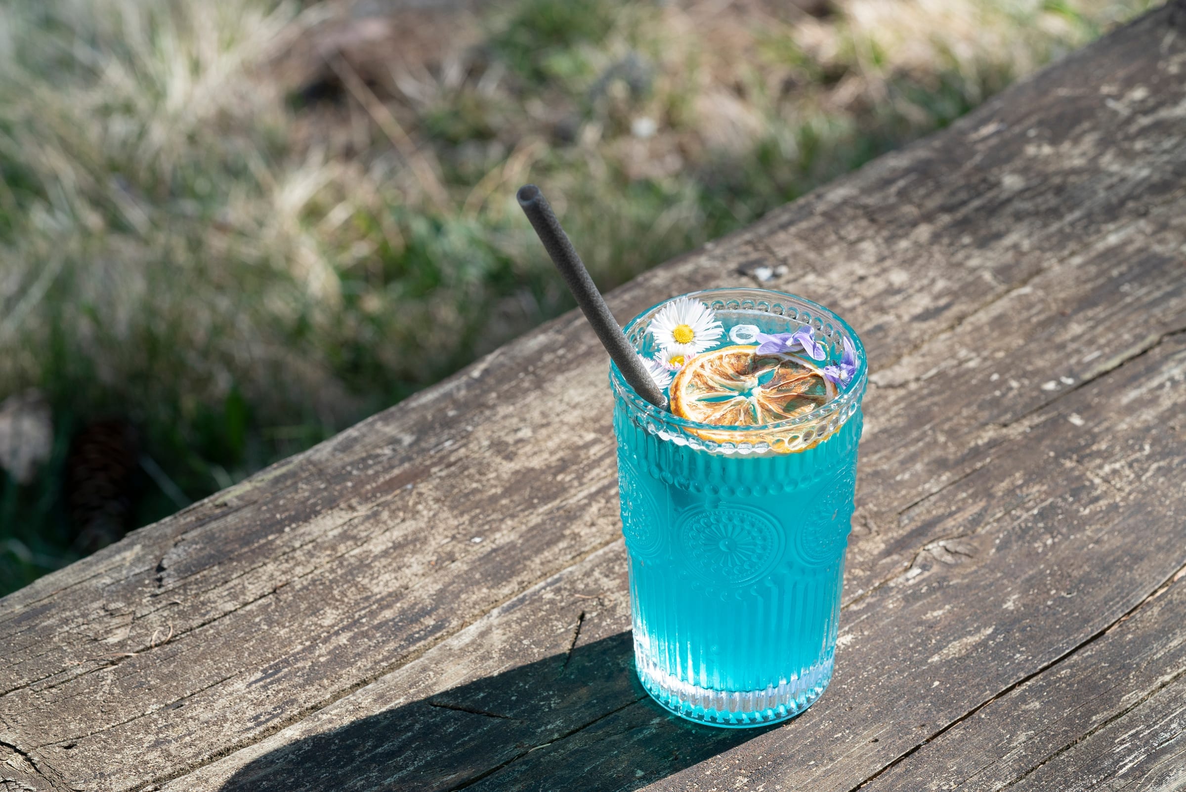 Cocktail signature bleu présenté dans le jardin du Grand Chalet
