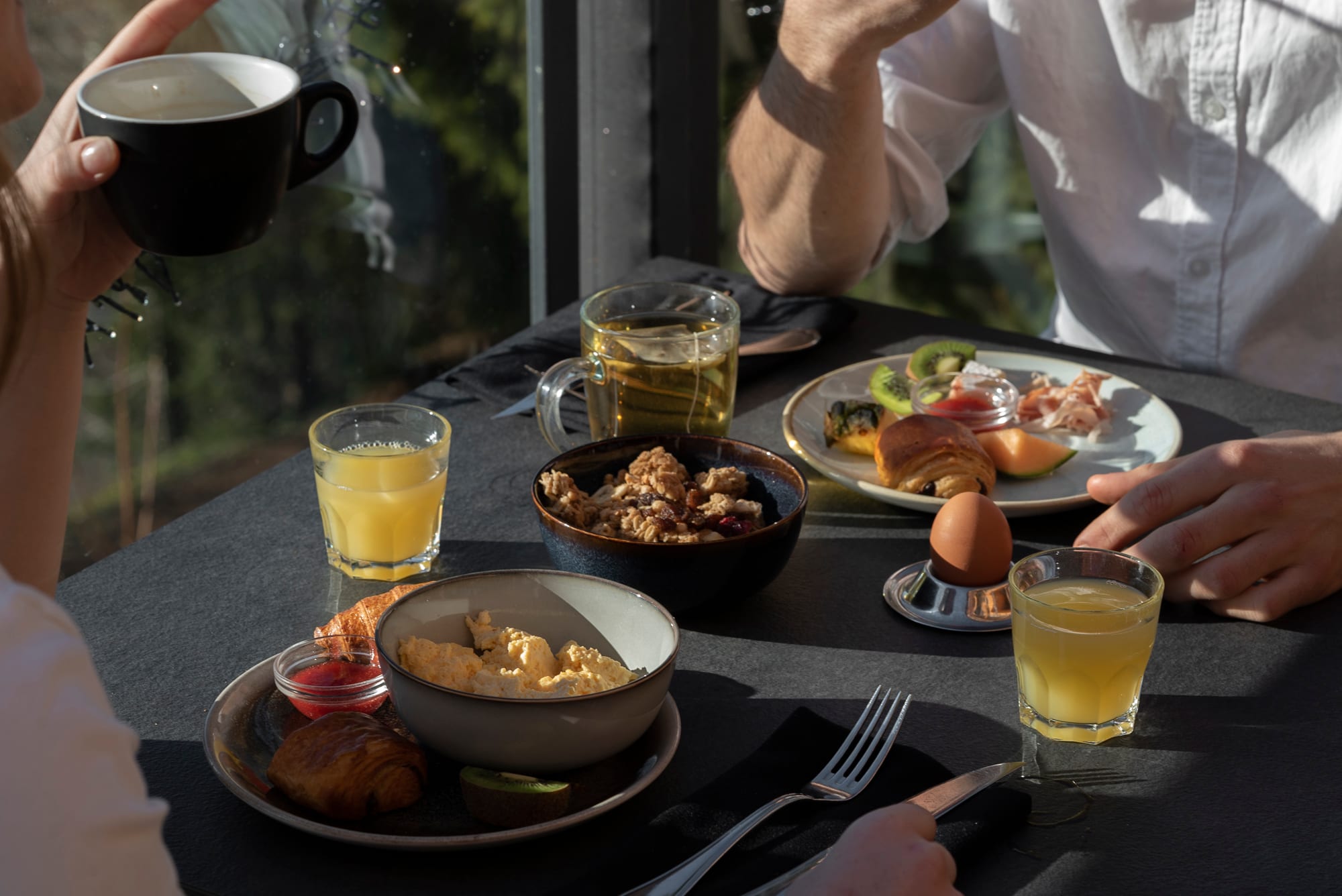 Table du petit-déjeuner face à la forêt, œufs, croissants et jus d'orange au Grand Chalet