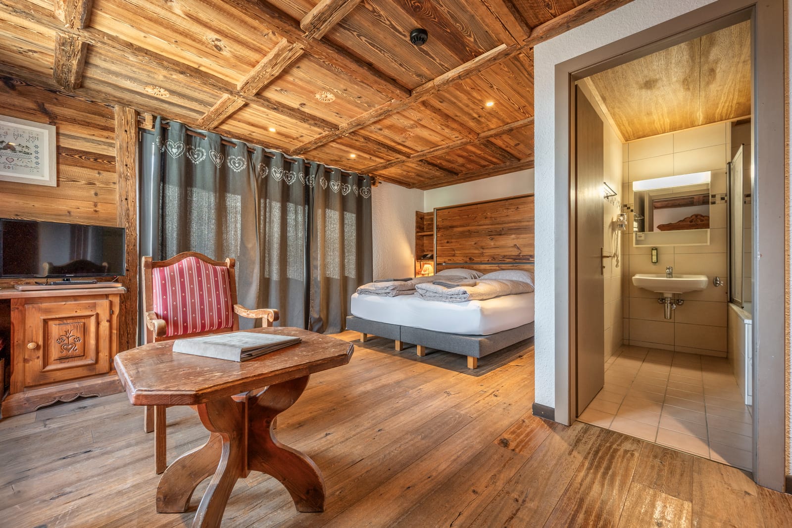 Chambre lumineuse avec tête de lit en bois et vue alpine